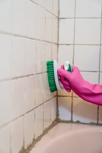 Hand in Rubber Glove Cleaning Bathroom Tiles