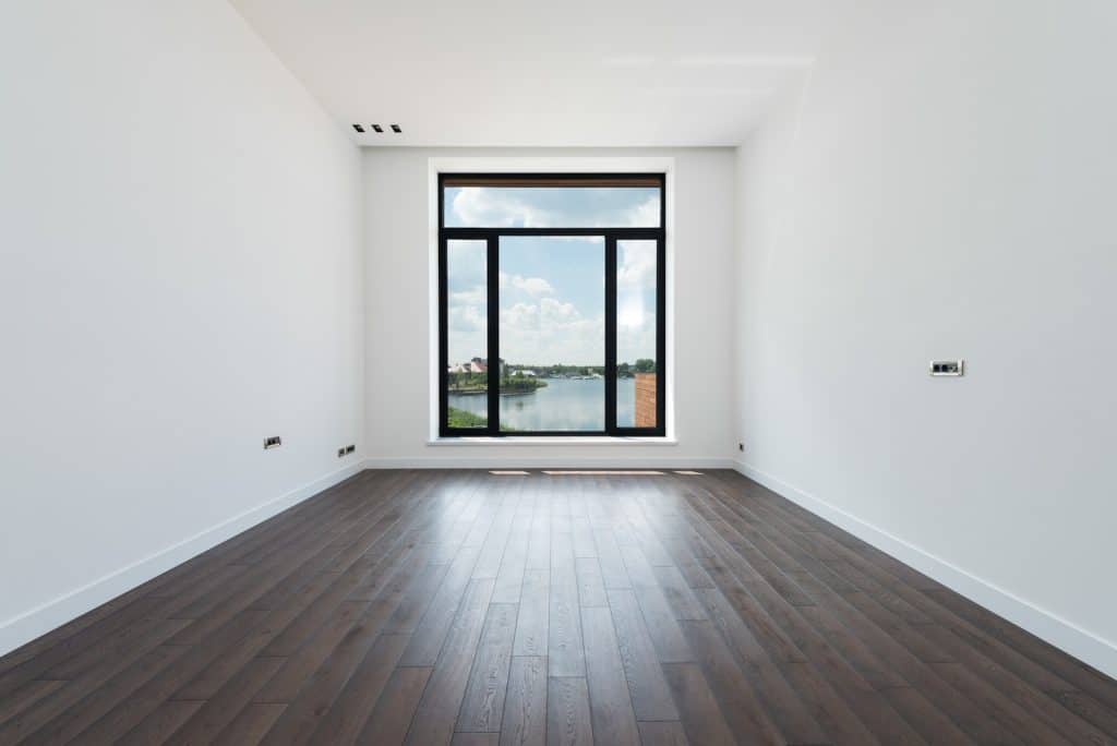 Interior of modern spacious light room with wooden laminate floor white walls and panoramic windows