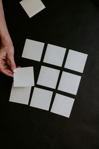 person holding white cards above a black table
